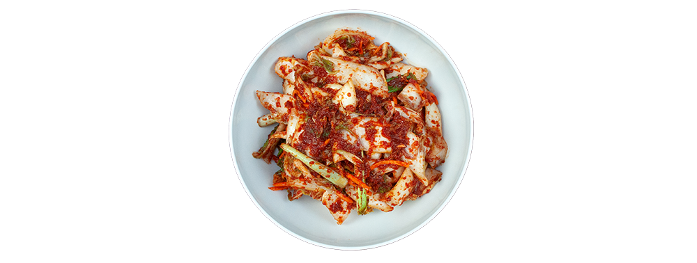 Weißer Teller mit frisch angemachtem Kimchi aus Chinakohl, Chiliflocken, Frühlingszwiebeln und Karotte, von oben fotografiert