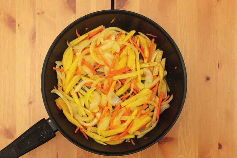 Kartoffelstifte, Zwiebel und Karotte in einer Pfanne