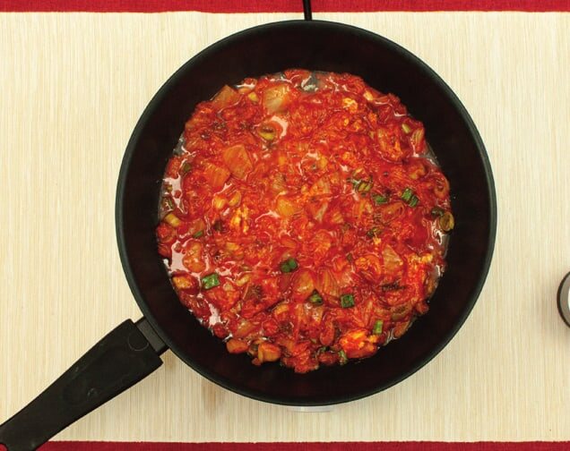 Kimchi mit Soße und Frühlingszwiebeln in der Pfanne