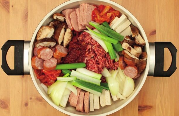 Topf mit roh angeordneten Zutaten, Hackfleisch und Würzsoße in der Mitte