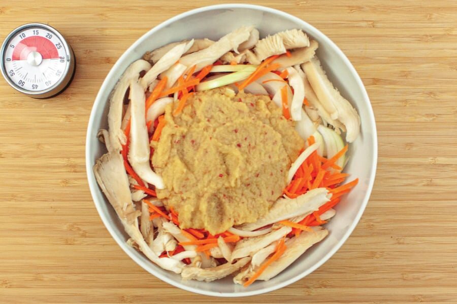 Schüssel mit Fleisch, Gemüse und Pilzen, darauf die pürierte Marinade, daneben ein Küchenwecker