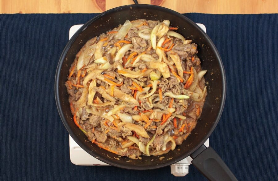 Pfanne mit mariniertem Fleisch, Zwiebeln, Pilzen und Karotten