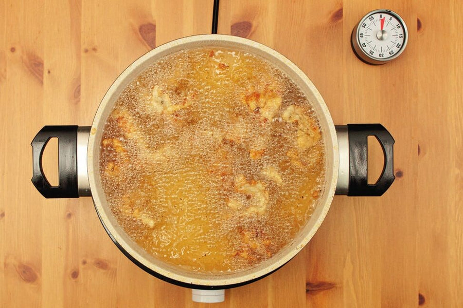 Hähnchen beim zweiten Frittieren im Topf, Küchenwecker daneben