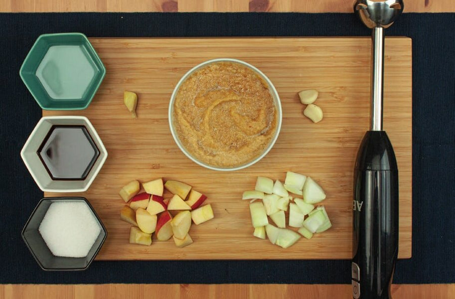 Apfel- und Zwiebelwürfel, Knoblauch, Schälchen mit Wasser, Sojasoße und Zucker, daneben die pürierte Soße und ein Pürierstab