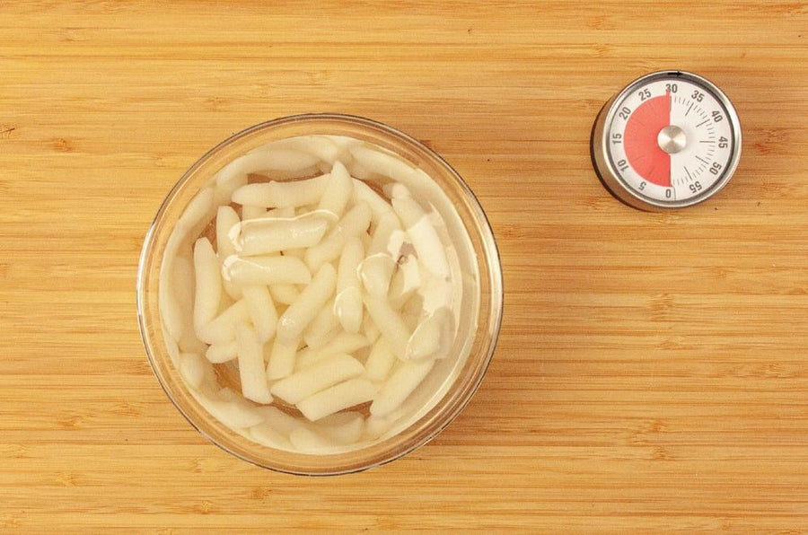 Reiskuchen in einer Glasschüssel mit Wasser, daneben ein Küchentimer